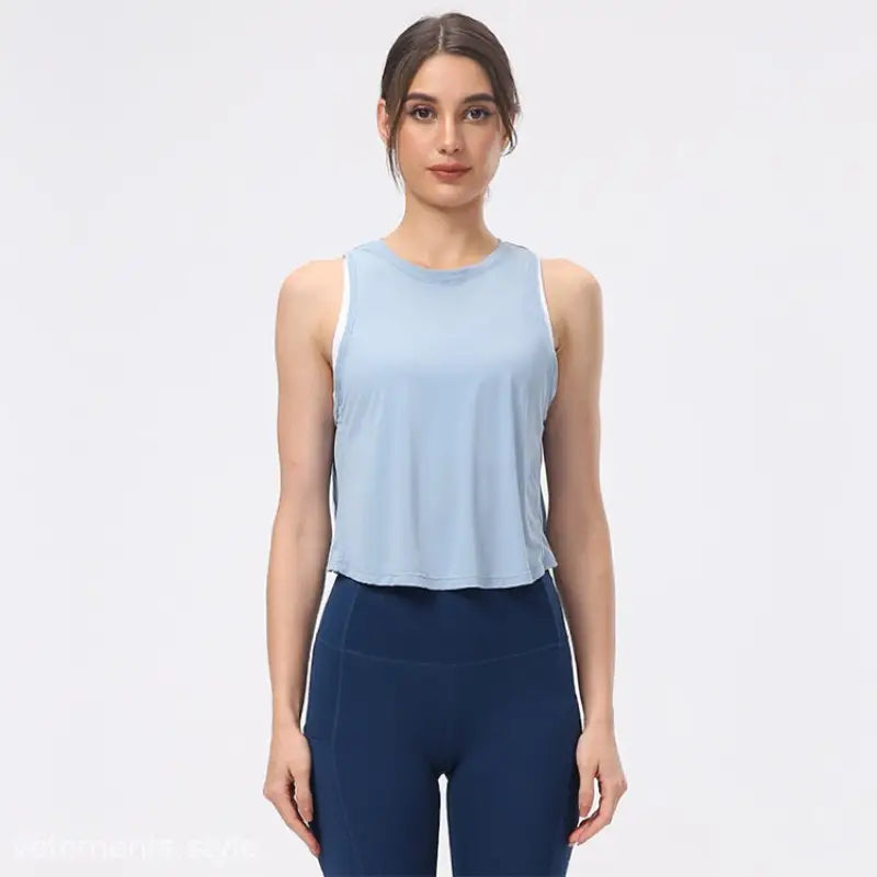 Woman wearing a light blue sleeveless top and navy blue leggings showcasing the Sporty Nylon Half Waist Blouse in Chinese Olive Green and Midnight Blue