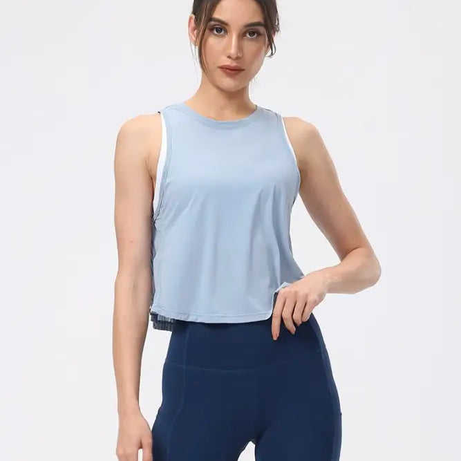 Woman wearing a light blue sleeveless top and navy blue fitted pants showcasing the Sporty Nylon Half Waist Blouse in Chinese Olive Green and Midnight Blue