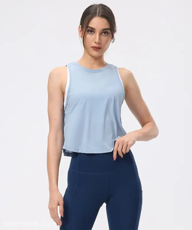 Woman wearing a light blue sleeveless top and navy blue fitted pants showcasing the Sporty Nylon Half Waist Blouse in Chinese Olive Green and Midnight Blue