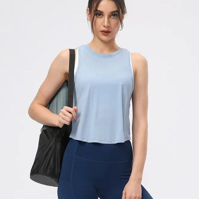 Young woman wearing a sporty nylon half waist blouse in Chinese Olive Green and Midnight Blue with navy leggings