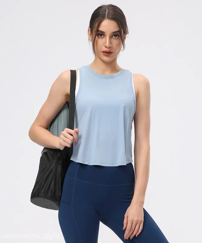 Young woman wearing a sporty nylon half waist blouse in Chinese Olive Green and Midnight Blue with navy leggings