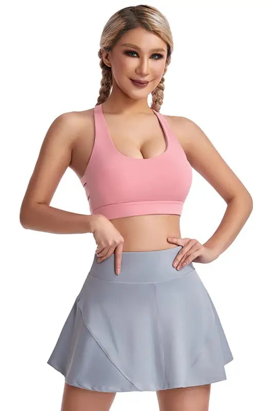 Woman in pink sports bra and gray skirt wearing a boost shape workout bra with steel ring
