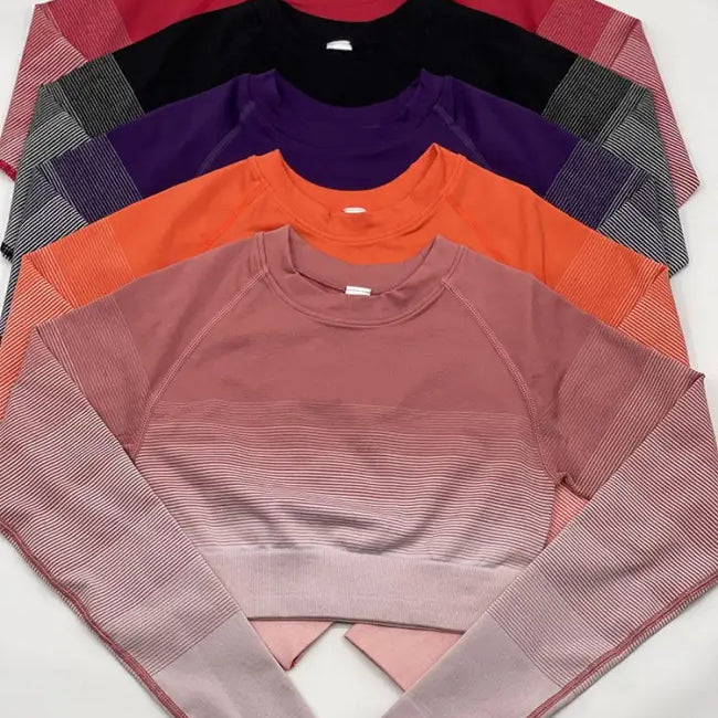 Stack of five athletic long-sleeved shirts with gradient and striped patterns, including purple long sleeve and orange pink pants
