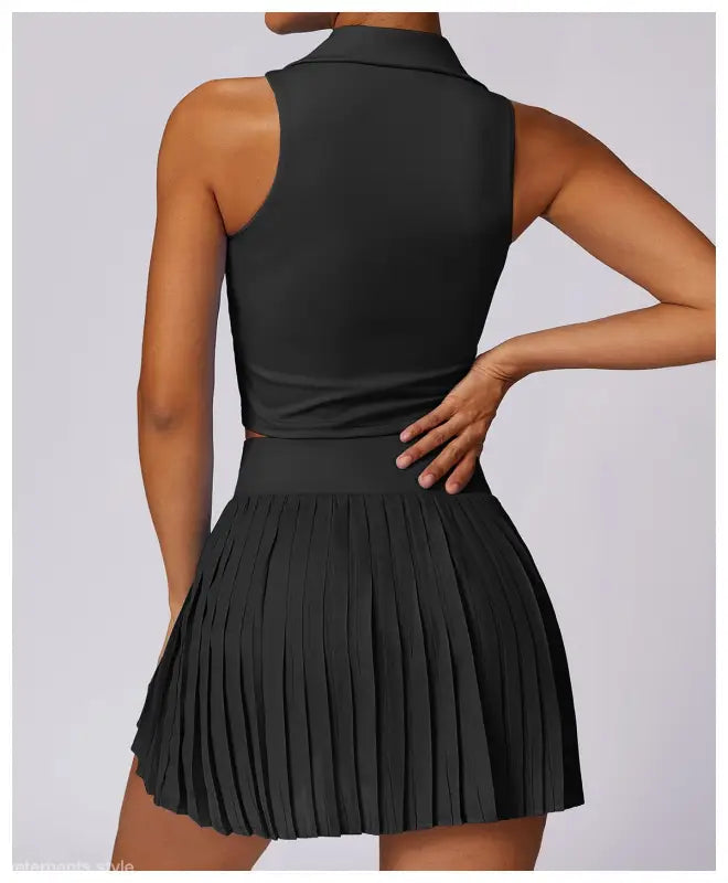 Black sleeveless top paired with pleated mini skirt in Swan White Suit style