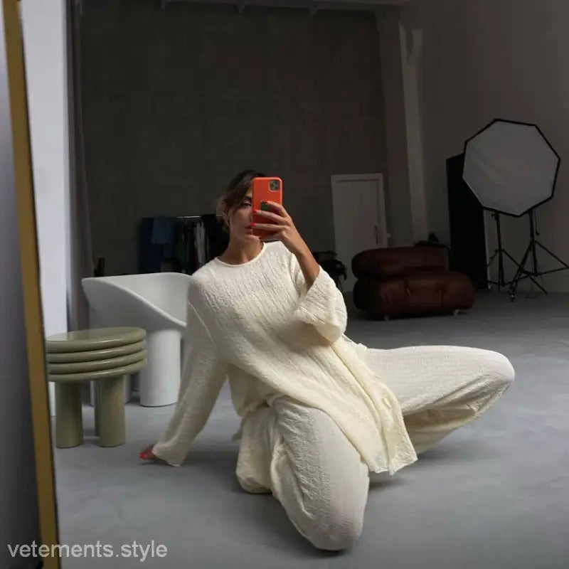 Person in all-white stitching crepe casual suit taking a mirror selfie on the floor