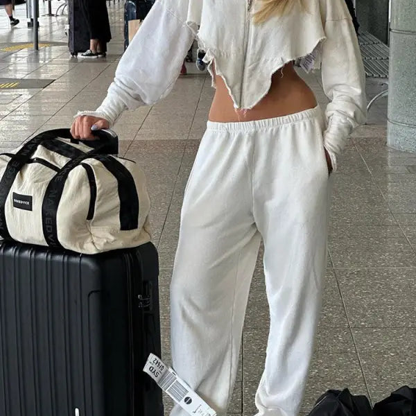 Woman in white sweatsuit with luggage in stylish casual sportswear for the sexy sweet girl