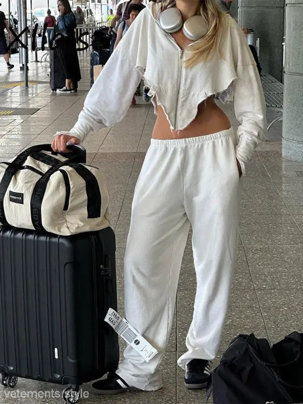 Woman in white sweatsuit with luggage in stylish casual sportswear for the sexy sweet girl