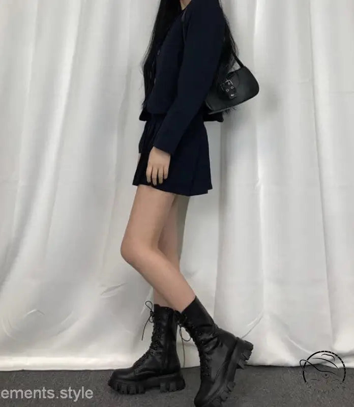 Woman in navy blue dress with stylish lace-up platform boots and black handbag