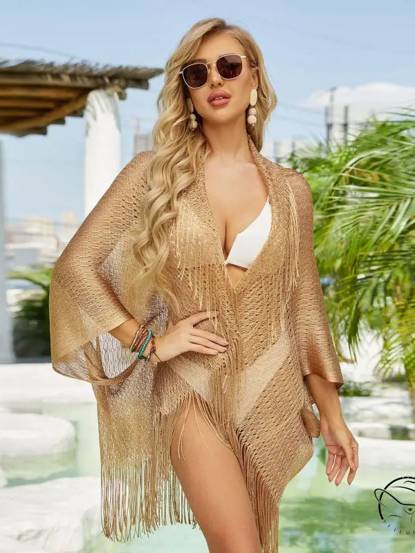 Blonde woman in Talma shawl beach cover with fringed gold sleeves and sunglasses