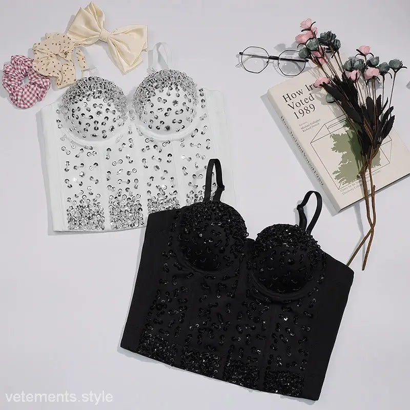 Black sequined three dimensional corset top with rhinestone bow on black background