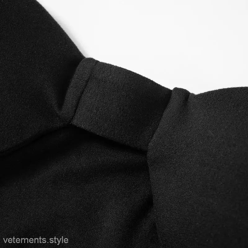 Black fabric knot detail on trendy open bone dress in asymmetric cutout bodycon midi style