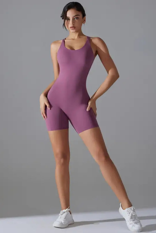 Purple sleeveless athletic bodysuit worn by a woman with white sneakers.