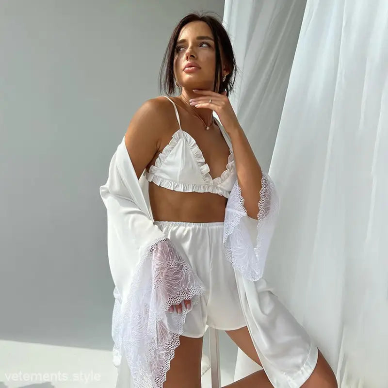 Woman in white lingerie and lacy robe posing with winter sexy stitching silk-like satin lounge set