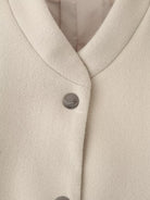 Cream-colored single breasted wool coat with silver buttons