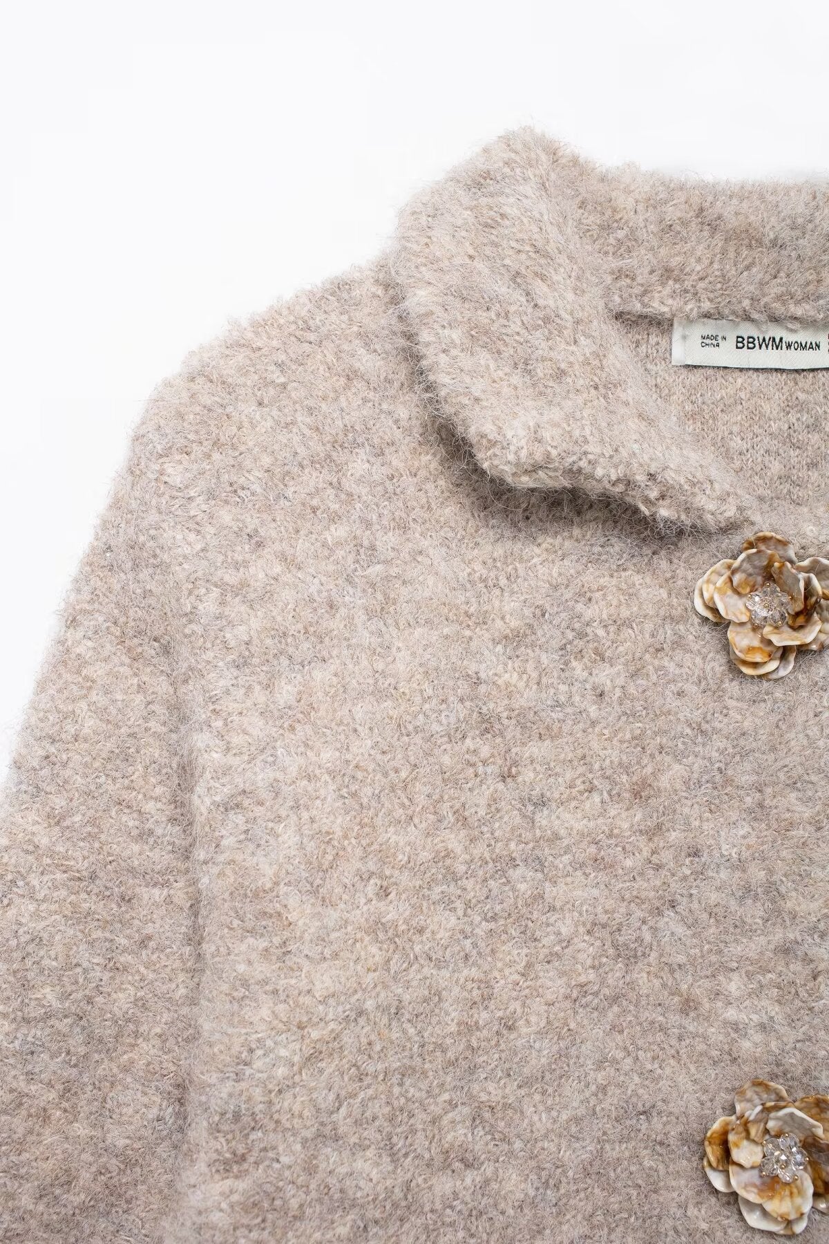 Elegant knitted cardigan with beige fluffy sweater, floral brooches, and Langry fashion label