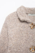Elegant knitted cardigan with beige fluffy sweater, floral brooches, and Langry fashion label