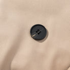 Casual long sleeve belt short trench coat with black button on beige fabric