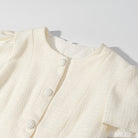 Cream-colored textured short sleeve bud cardigan with round buttons and high neckline