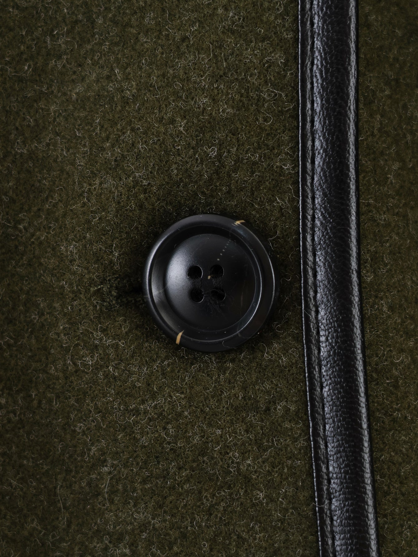 Black button with four holes on textured fabric, Langry fashion coat detail