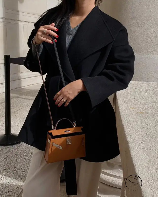 Elegant woolen coat with black leather crossbody bag, gold hardware, orange interior