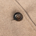 Elegant langry autumn woolen coat with brown four-hole button on beige fabric