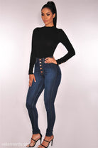 Woman in a black long-sleeved top and high-waisted button-up jeans in skinny denim blue casual