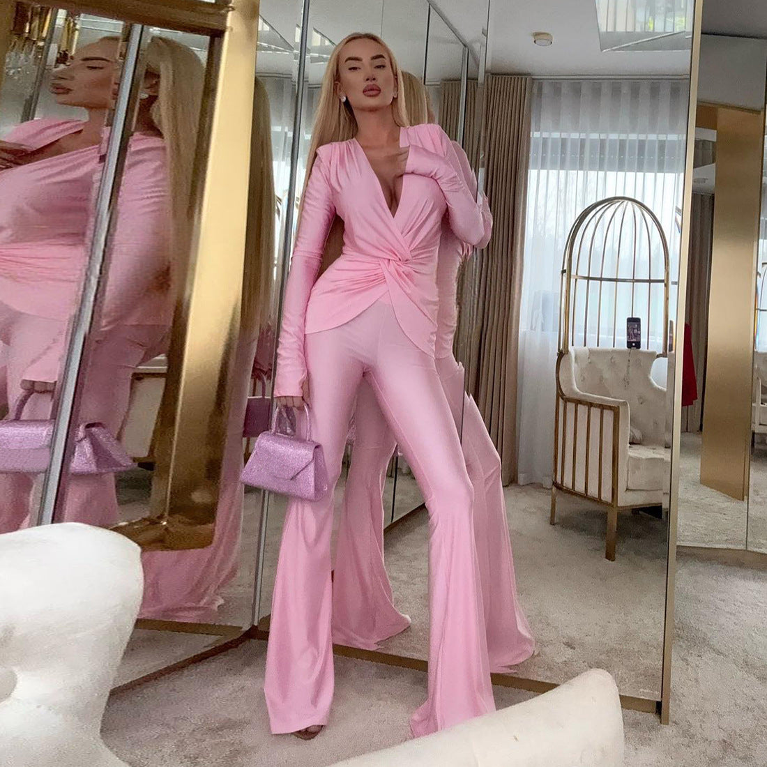 Pink satin long sleeve jumpsuit with deep V-neck and flared pants