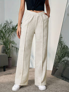 Cream-colored wide leg trousers featuring pleats and pockets ideal for modern fashion