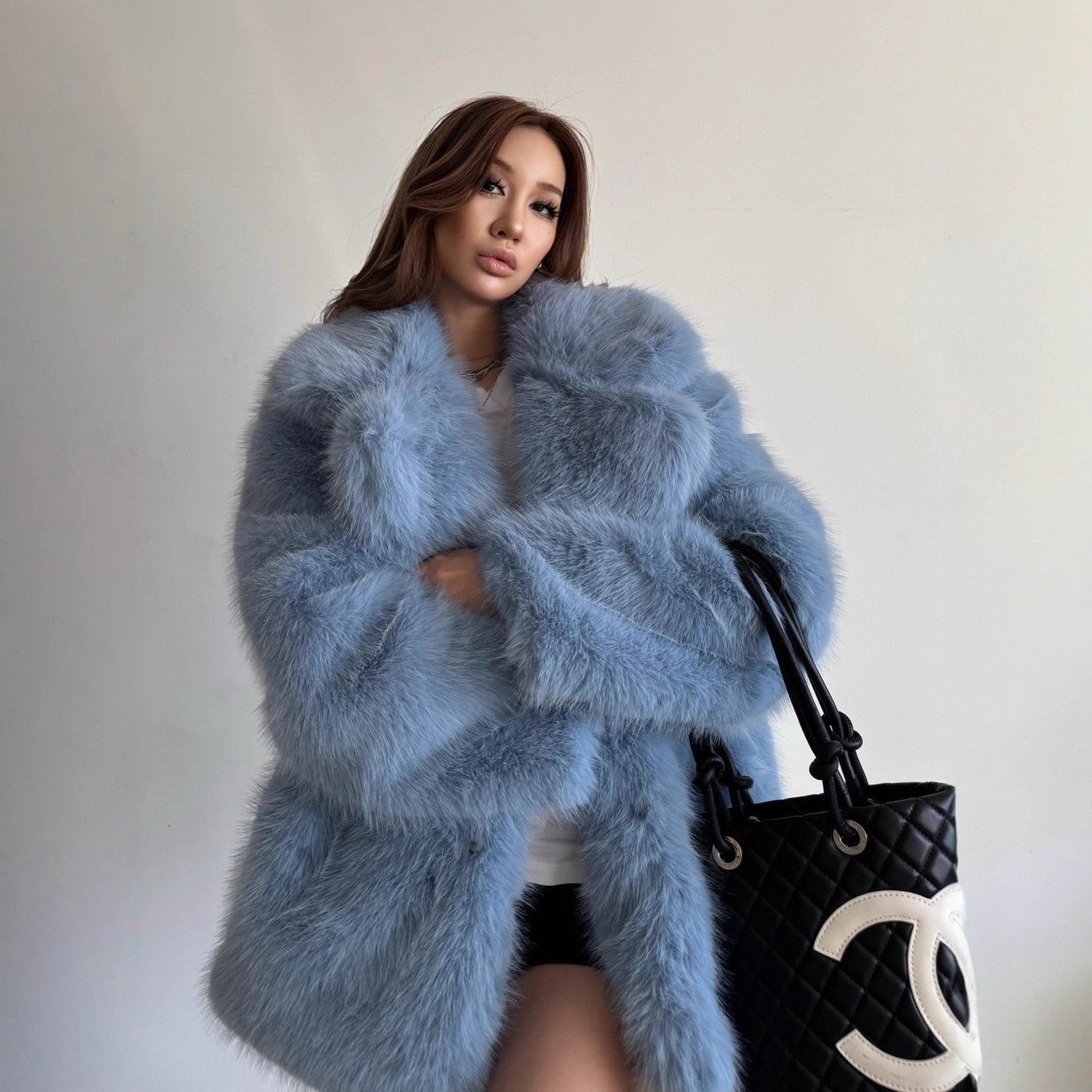 Light blue fluffy faux fur coat with Chanel logo on black tote bag
