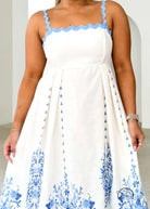 Attractive backless dress in white with blue floral embroidery and scalloped straps