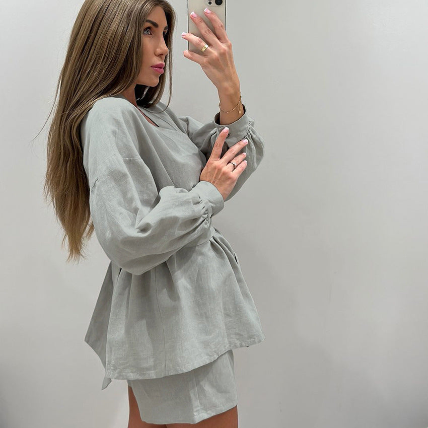 Woman modeling loose casual cotton pajamas with sage green long-sleeved peplum top and matching shorts
