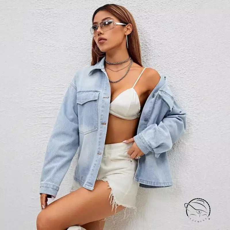 Fashionable woman in loose langry denim coat, white bralette, and distressed shorts