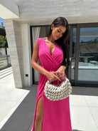 Woman in pink dress holding a white woven handbag showcasing elegant fashion ملابس