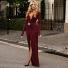 Burgundy velvet langry evening dress with long sleeves, high slit, and waist brooch