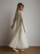 Cream-colored knitted cardigan with fur trim over sleeveless dress