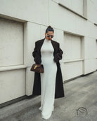 Elegant white maxi dress with black coat and brown handbag