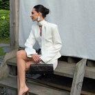 Elegant langry fashion white high-neck blouse with bell sleeves and black clutch bag in waist-tight blazer hip skirt two-piece set