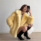 Yellow fluffy faux fur coat with black boots and white handbag