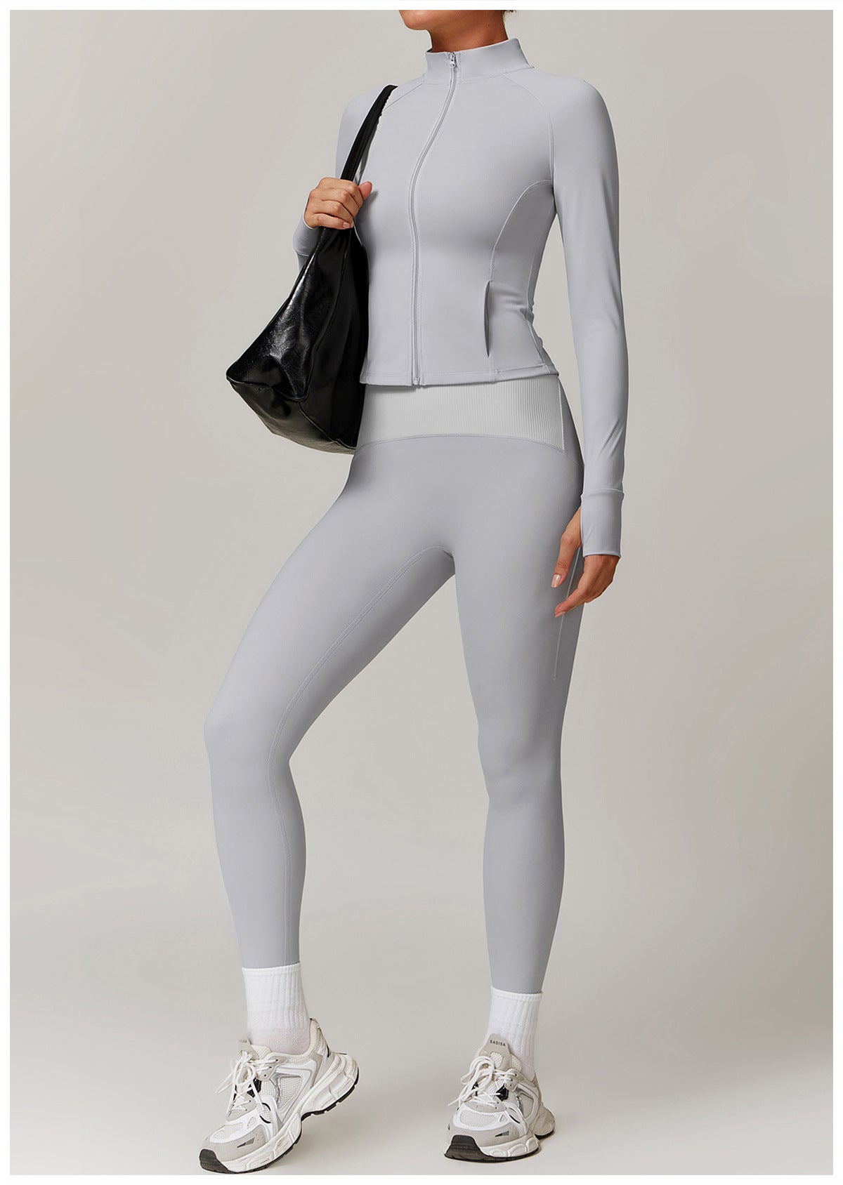 Light grey athletic two-piece set featuring a zip-up jacket and leggings, paired with sneakers
