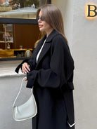 Sleek minimalist white Langry handbag with curved silhouette in fashion coat