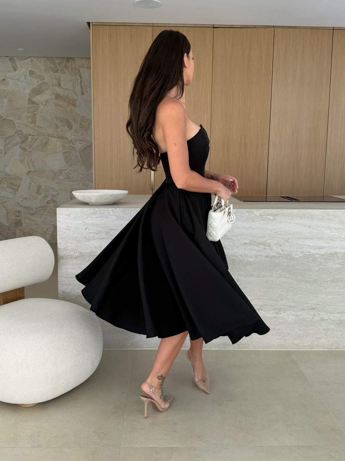 Woman in a black strapless dress, showcasing the elegance of Gorgeous Midi Dress fashion