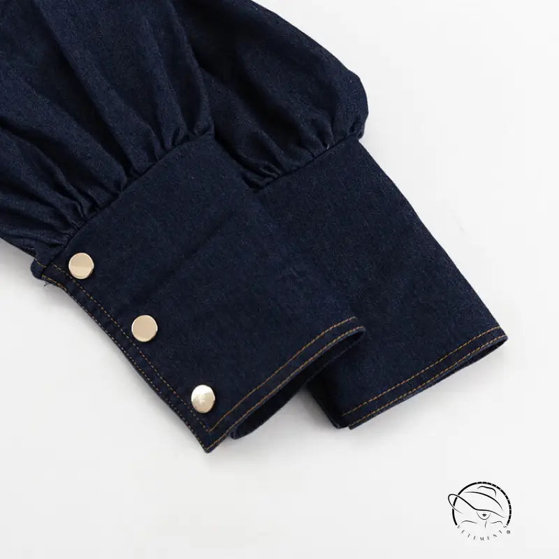 Dark blue denim shirt cuff with three gold buttons on fashionable dress