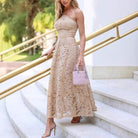Woman in a beige lace dress with a pink handbag, showcasing elegant langry fashion ملابس