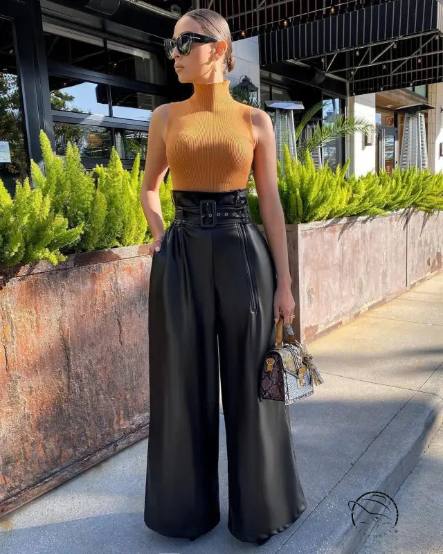 Woman in mustard turtleneck and high-waist faux leather pants with handbag