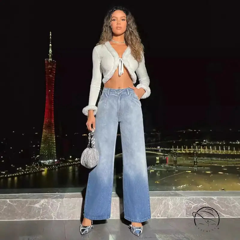 Woman in white fluffy crop top and high-waist denim trousers holding silver handbag