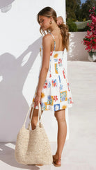 Woman in langry summer floral print maxi dress with straw tote
