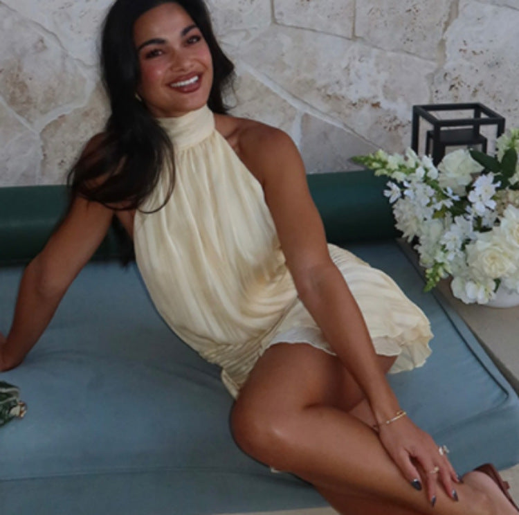 Woman in a yellow halter dress, showcasing the latest fashion in ملابس with a stunning backless design