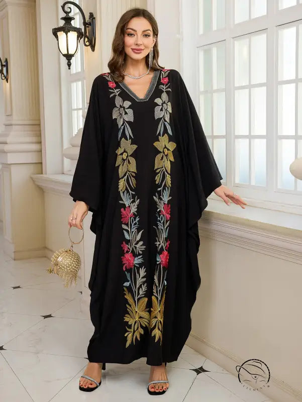 Elegant embroidered Middle East kaftan dress with black floral pattern, gold accents, V-neckline, and long sleeves