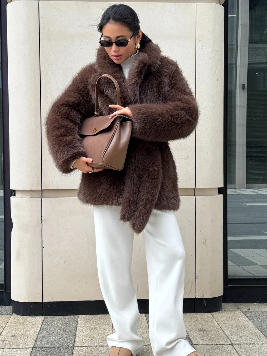 Brown faux fur coat with white pants and tan handbag in Langry fashion