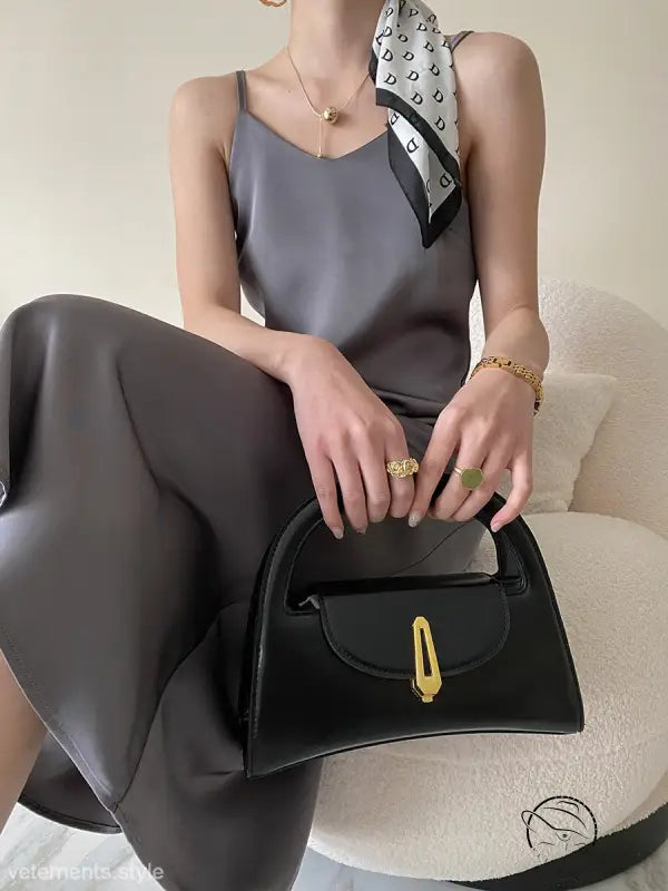 Obsidian black leather handbag with gold hardware on acetate satin dress